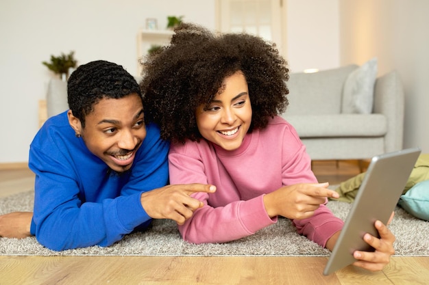 Coppia africana che utilizza il tablet impegnandosi nel divertimento digitale a casa