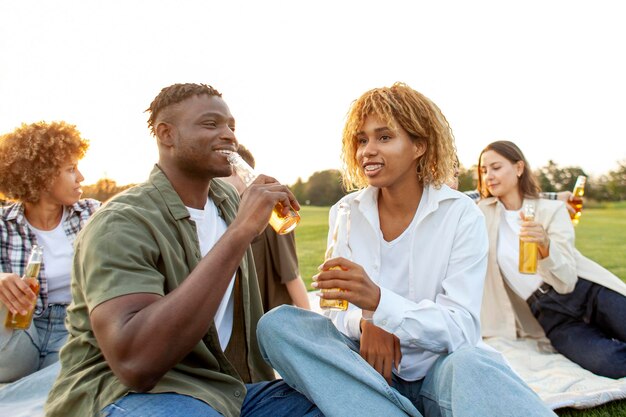 coppia afroamericana con una bottiglia di birra in mano e che parla nel parco all'aperto uomo e donna che bevono