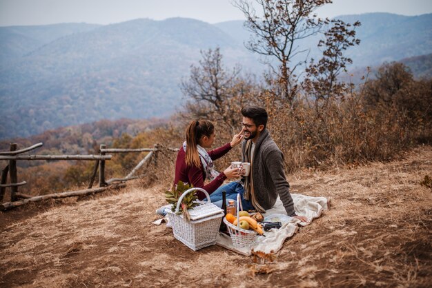 Coppia al picnic seduti e bere il tè.