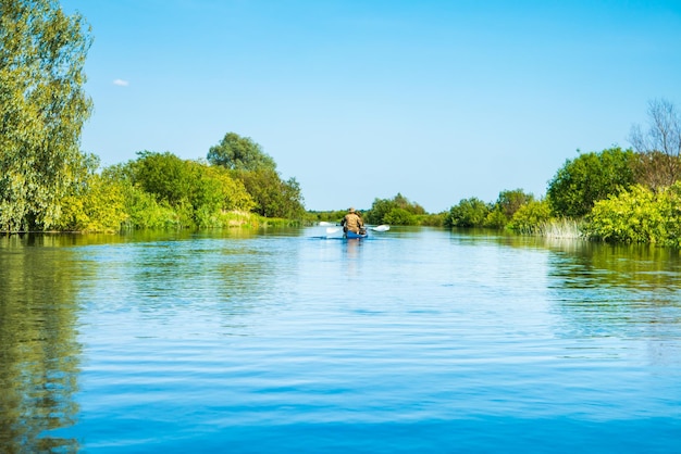 Coppia al viaggio in kayak sul fiume blu paesaggio e foresta verde con alberi cielo blu nuvole d'acqua