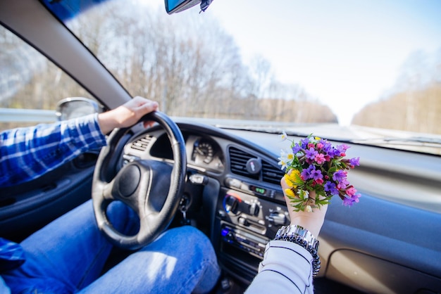 Coppia all'interno di auto concetto di viaggio in auto donna tenere piccoli fiori bouquet