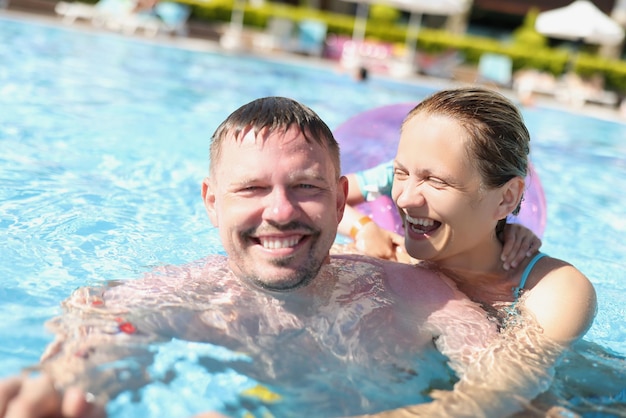 Coppia allegra in posa per una foto in piscina in resort di lusso