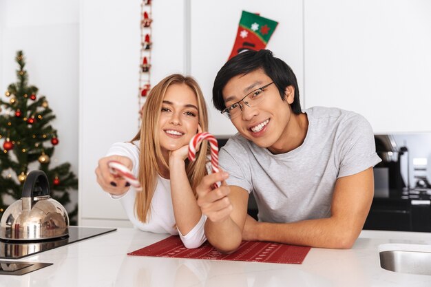 coppia allegra, uomo e donna in piedi nella cucina luminosa e che tiene le caramelle di Natale