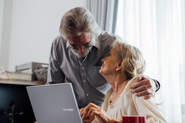 Coppia anziana di nonno e nonna sani che utilizzano il computer portatile per l'intrattenimento e lo shopping