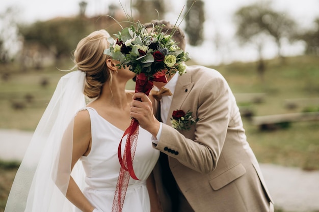 Coppia appena sposata. Lo sposo sta baciando la sposa. una coppia innamorata si nascose dietro un bouquet da sposa