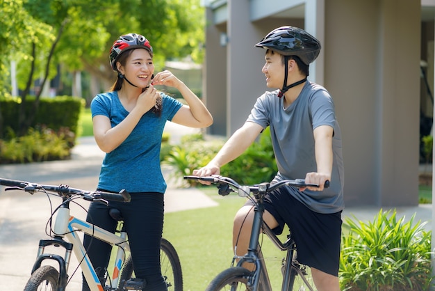 Coppia asiatica che indossa un casco mentre si prepara per un giro in bicicletta nel suo quartiere per la salute quotidiana e il benessere, sia fisico che mentale.