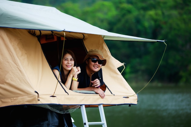 Coppia asiatica che si rilassa nella tenda sul tetto vicino al fiume