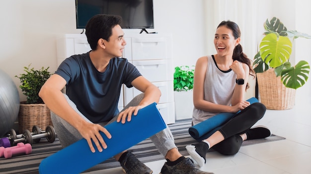 Coppia asiatica giovane amante che parla dopo aver giocato a yoga ed esercizio fisico a casa.