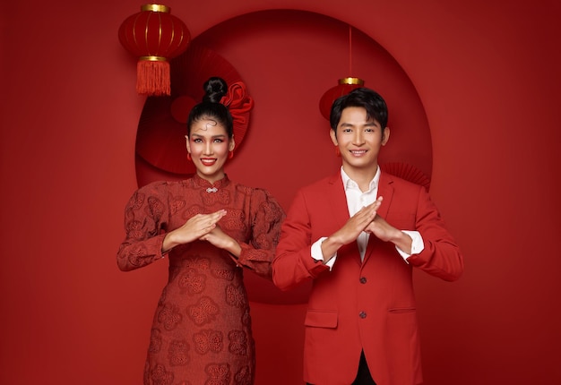 coppia asiatica in abiti casuali rossi con un gesto di congratulazioni felicitando il nuovo anno cinese