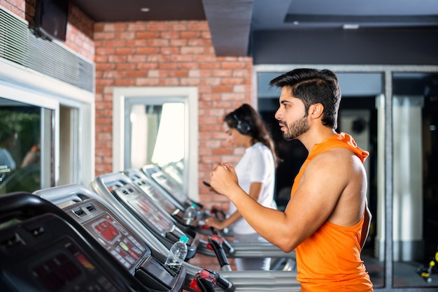 Coppia attraente asiatica indiana che fa un programma di allenamento cardio nel centro fitness o palestra, foci selettivi - concetto di salute e fitness