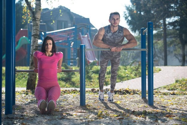 Coppia attraente che fa esercizio Crossfit con Dips Bar nell'area del parco cittadino Formazione ed esercizio per Endurance Stile di vita sano Concept Outdoor