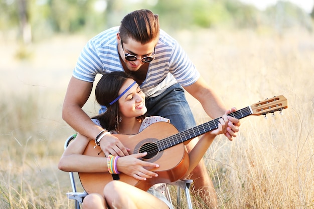 Coppia attraente che suona la chitarra, all'aperto