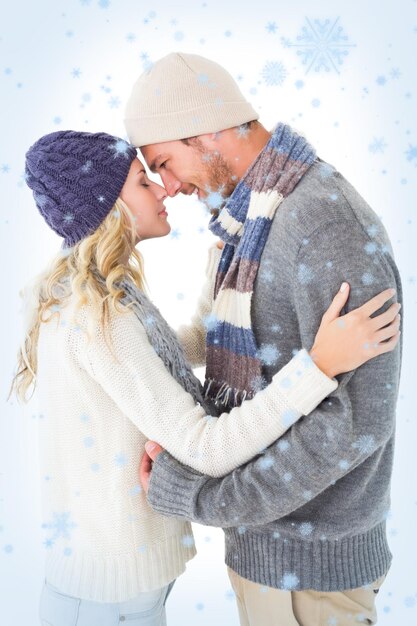 Coppia attraente in moda invernale che abbraccia contro la neve che cade
