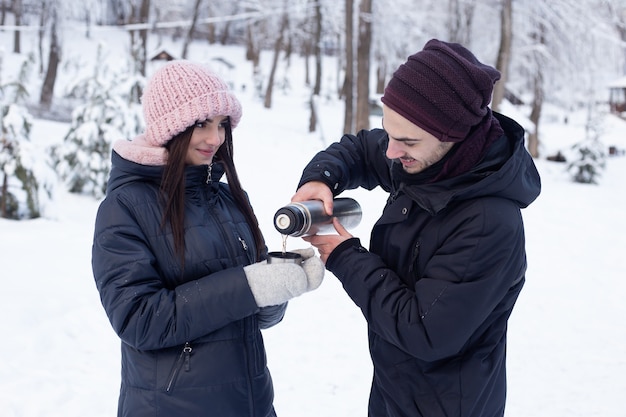 Coppia bere il tè che versa da un thermos a winter park