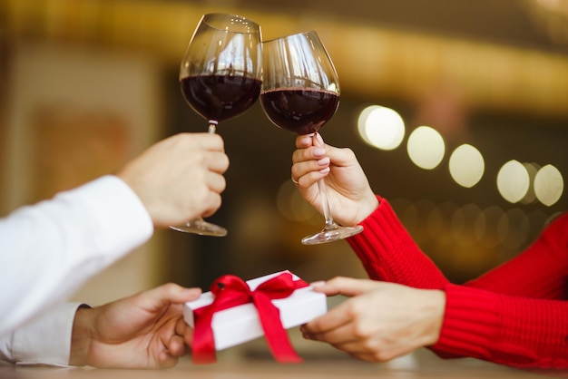Coppia bicchieri tintinnanti con vino rosso Gli amanti si scambiano regali Bella cena romantica