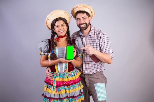 Coppia brasiliana vestiti da festa junina arraial festa de sao joao fidanzato e fidanzata con smartphone schermo verde