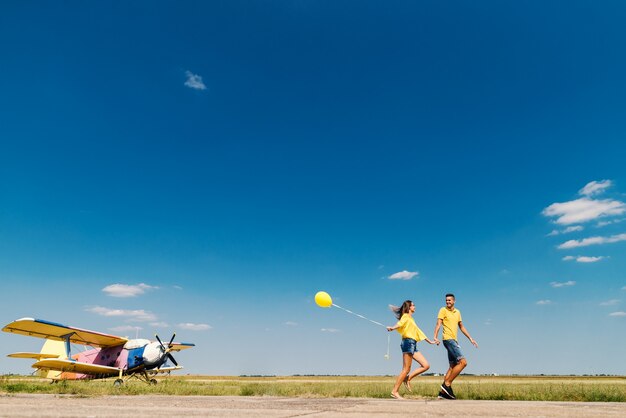 Coppia carina in esecuzione e mano nella mano. In campo e in aereo. Dominando i colori blu e giallo.