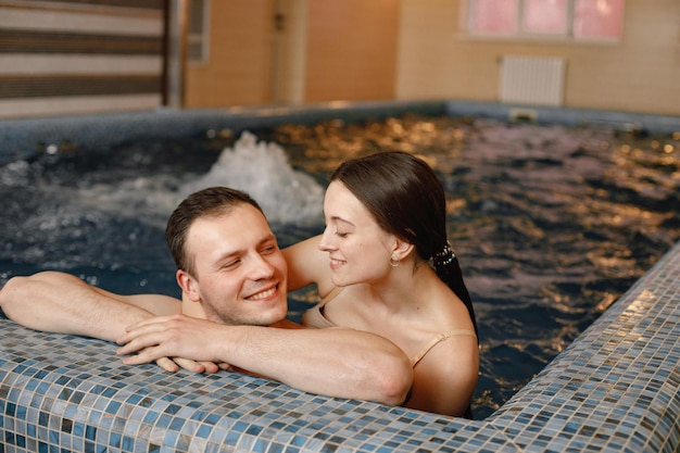 Coppia carina parlando e abbracciando vicino a bordo piscina nella piscina interna