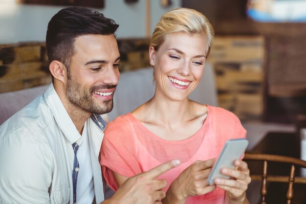 Coppia carina seduto nel caffè guardando smartphone