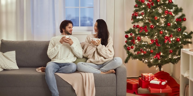 Coppia celebrazione capodanno vicino all'albero di Natale a casa