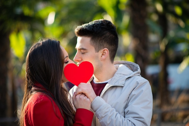 Coppia che copre il loro bacio con un cuore