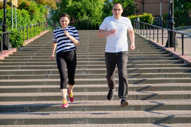 Coppia che corre sulle scale in città, uomo e donna maturi insieme, stile di vita sano di fitness sportivo attivo di persone di mezza età