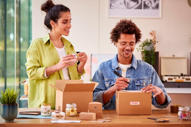 Coppia che esegue attività online da casa Imballaggio ed etichettatura di candele boutique pronte per la spedizione