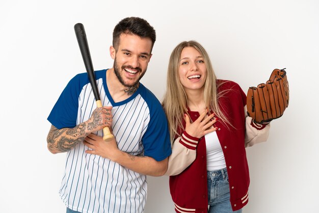 Coppia che gioca a baseball su sfondo bianco isolato sorridendo molto mentre mette le mani sul petto