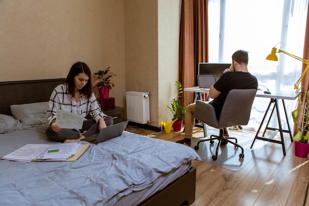 Coppia che lavora a casa isolamento domestico donna sul letto uomo sullo spazio della copia della sedia dell'ufficio