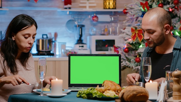 Coppia che mangia un pasto festivo guardando lo schermo verde orizzontale