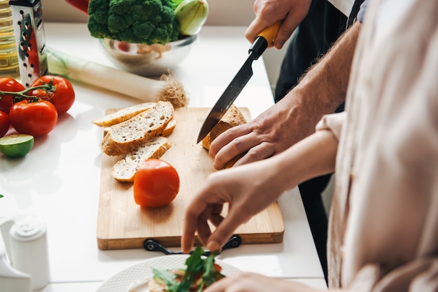 Coppia che prepara il pranzo insieme preparando insalata e tagliando un pasto sano per la cena romantica