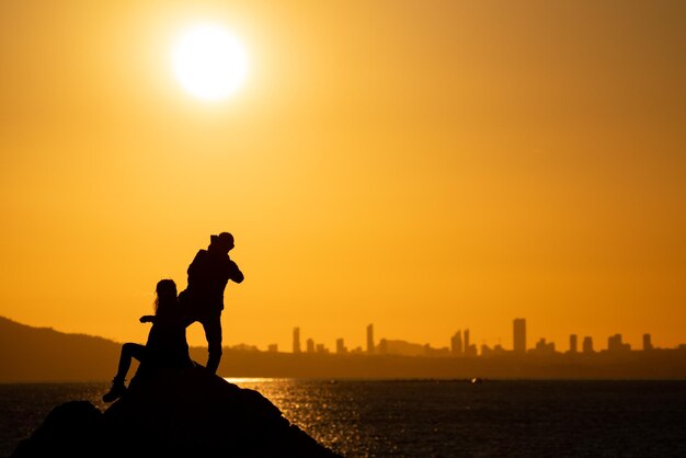 Coppia che scatta foto sociali al tramonto con lo skyline della città sullo sfondo