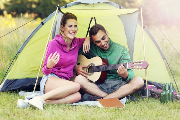 coppia che si accampa nella foresta e suona la chitarra