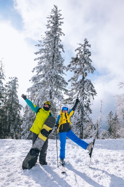 Coppia che si diverte alla stazione sciistica uomo con snowboard donna con sci