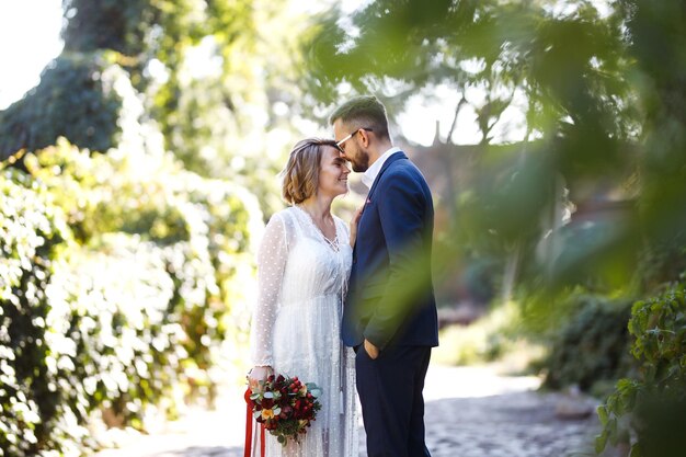 Coppia che si gode momenti romantici mentre si cammina nel parco Elegante sposa e sposo che posano e si baciano