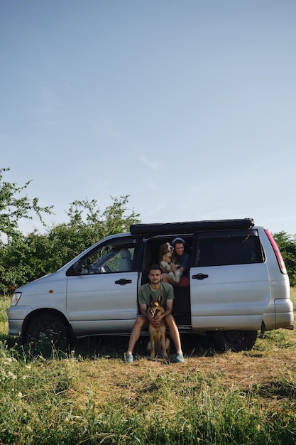 Coppia con cani che viaggiano insieme sul trasporto di minivan retrò con pastore australiano e tedesco