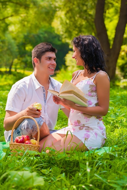 Coppia con libro e mela nel parco