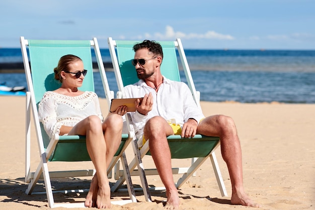 Coppia con tavoletta digitale sulla spiaggia