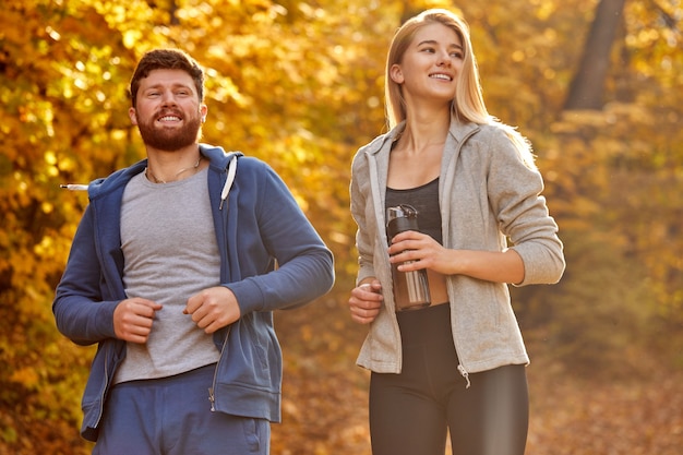 coppia corrono insieme nella foresta di autunno, godono di uomo sportivo atletico e donna in abiti sportivi