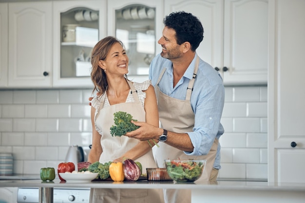 Coppia cucina e verdura in cucina insieme cibo sano e nutrizione felice con l'abilità dello chef a casa Uomo donna e cucina con sorriso verdure fresche biologiche e preparazione insalata per pasto