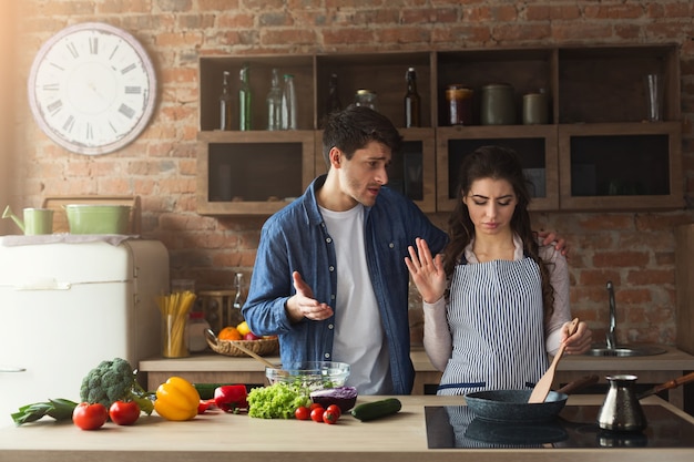Coppia cucinare una cena sana e litigare nella loro cucina loft a casa. Preparazione dell'insalata di verdure.