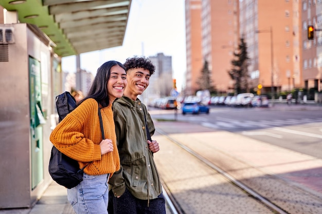 Coppia di adolescenti in attesa alla fermata del treno o del tram giovani studenti con una chitarra e un ukulele nella sua custodia