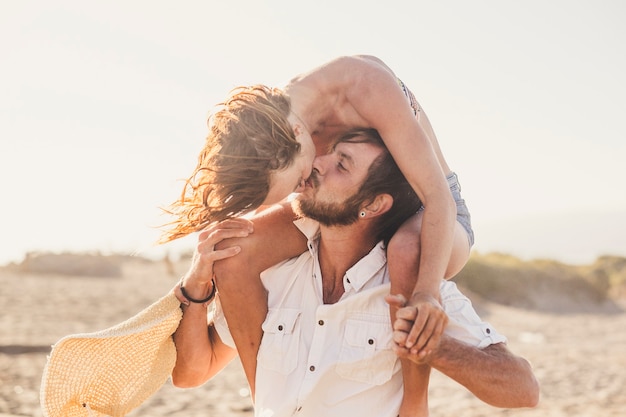 Coppia di adulti che si divertono e si baciano - bellissimo uomo in piedi e bella donna sul ragazzo che lo bacia - relazione romantica e amorevole