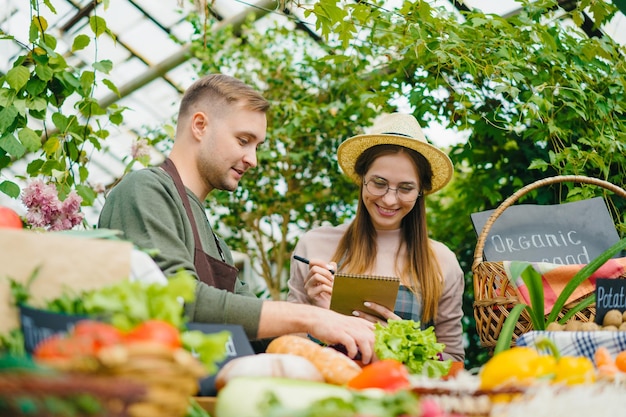 Coppia di agricoltori che parlano di vendita di alimenti biologici al mercato a discutere di affari