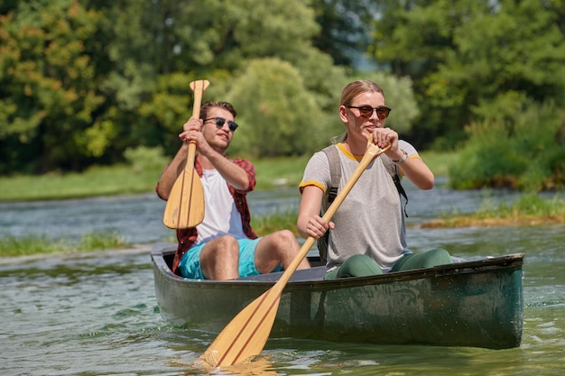 Coppia di amici esploratori avventurosi stanno andando in canoa in un fiume selvaggio circondato dalla bellissima natura