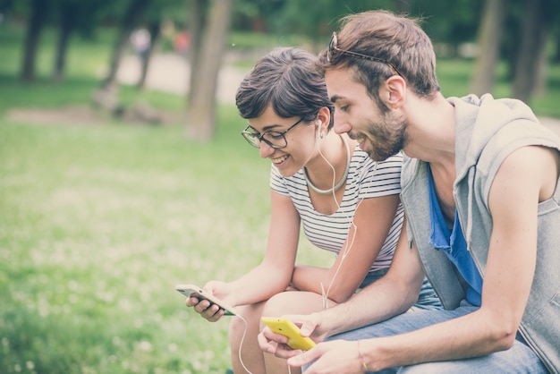 coppia di amici giovane uomo e donna tramite smartphone