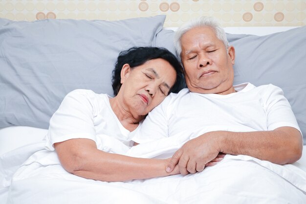 Coppia di anziani asiatici dormire a letto in camera da letto.