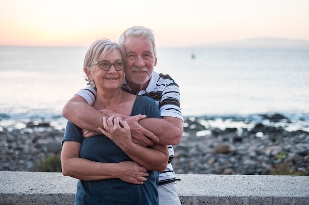 Coppia di anziani che si divertono in spiaggia con tanto amore - si sono ritirati insieme - donna con occhiali e uomo con sfondo marino