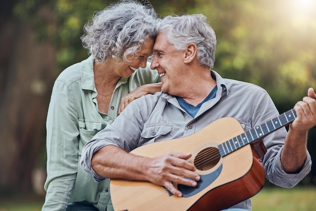 Coppia di anziani chitarra e amore in un parco insieme suonando una romantica canzone di musica d'amore o affetto per la moglie Romance uomo anziano e donna in pensione suonano strumenti a corda e ridono all'aperto nella foresta