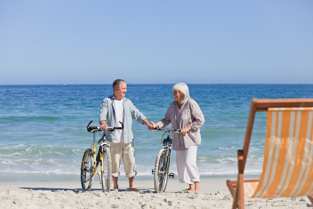 Coppia di anziani con le loro biciclette sulla spiaggia